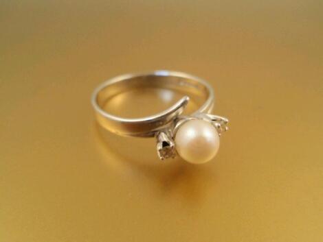 An 18ct white gold twist ring set with a pearl flanked by two small diamonds