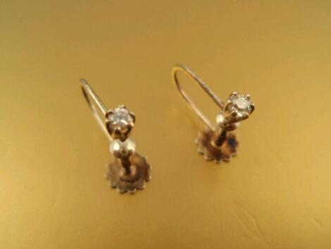 A pair of tiny diamond stud earrings with screw backs