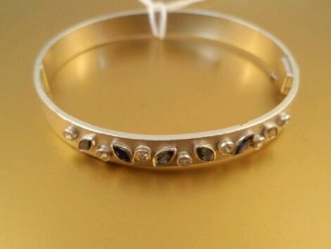 A custom made hinged bangle set with six marquise cut blue sapphires and