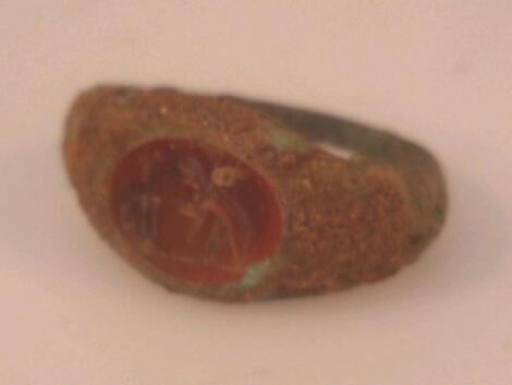 A Roman bronze ring set with an oval carnelian intaglio crudely engraved