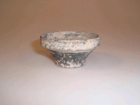 A small Roman black pottery bowl with a vertical mouth and body tapering