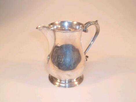 A George VI silver pear shaped jug with an acanthus capped scroll handle