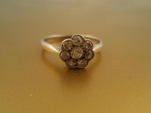 A diamond flower head cluster ring of eight close set stones in white metal