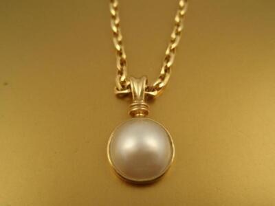 A half pearl bead pendant in 9ct gold with a fancy belcher chain