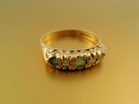 A 9ct gold dress ring set in line with three round emerald and two tiny