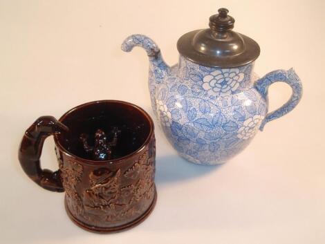 A treacle glaze frog mug moulded in relief with topers and vine