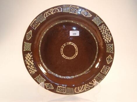 A modern slipware charger trailed in yellow and green with geometric motifs