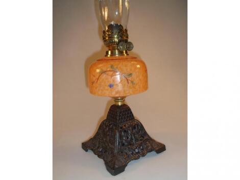 A late Victorian oil lamp with orange glass reservoir painted with flowers