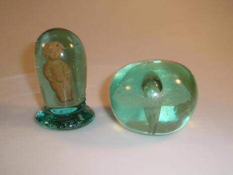 A green glass dump internally decorated with a buff glaze figure of a child