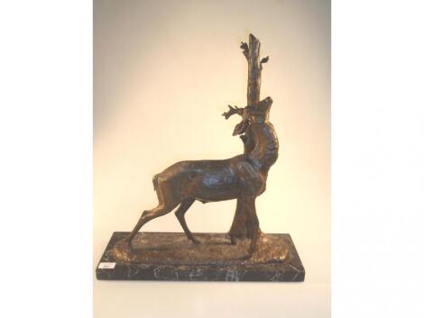 A gilded spelter figure of a deer against a tree trunk on black veined marble plinth