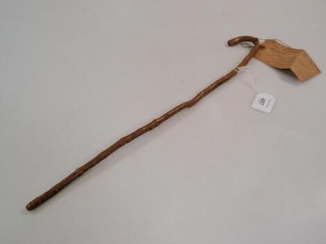 A Swagger stick, formed from a walking stick shape branch, bearing a label