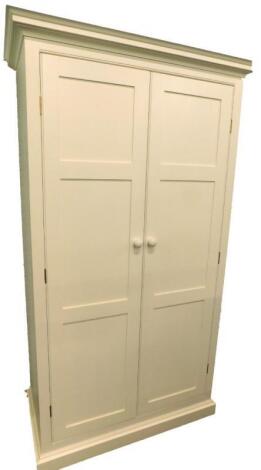 A cream painted two door wardrobe