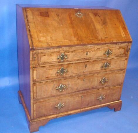 A George I walnut bureau with fall flap revealing a fitted interior over