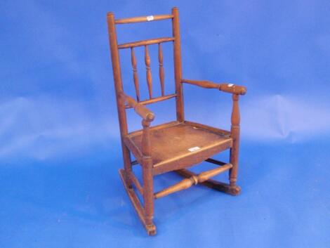 An early 19th century elm child's rocking chair with spindle back turned