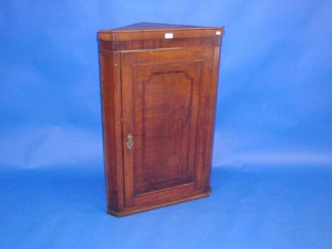 A George III oak hanging corner cupboard with single door