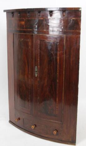 An early 19thC mahogany and part inlaid hanging corner cupboard