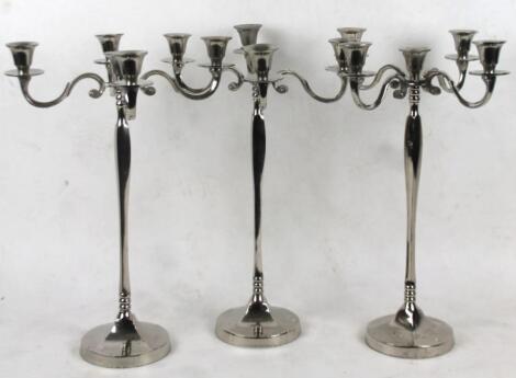 A set of three chrome plated five branch candelabra