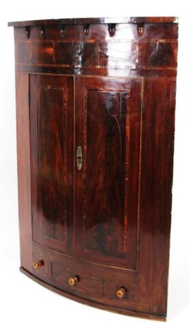 An early 19thC mahogany and part inlaid hanging corner cupboard