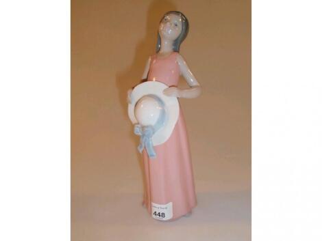 A Lladro figure of a young girl wearing a pink dress