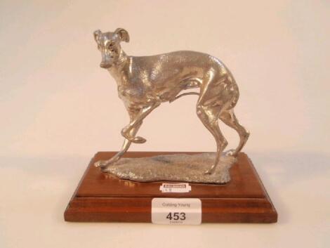 A silvered metal figure of a whippet on rectangular mahogany base