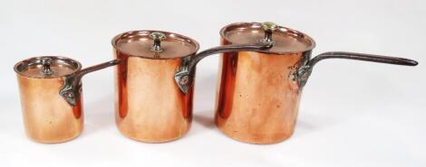 A graduated trio of copper lidded saucepans