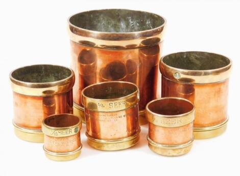 A set of six graduated copper and brass vessels