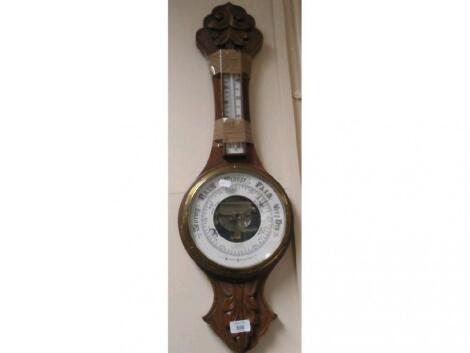 An Edwardian carved oak aneroid wheel barometer