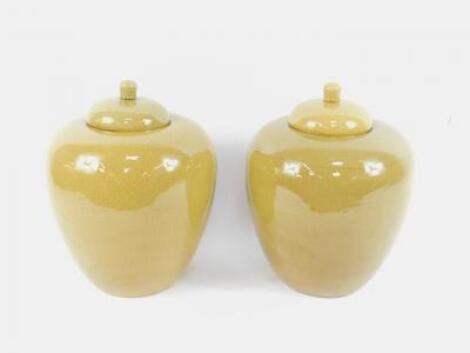 A pair of Chinese late 20thC crackle glaze olive coloured jars and covers