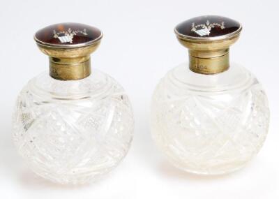 A pair of George V silver tortoiseshell and cut glass perfume bottles