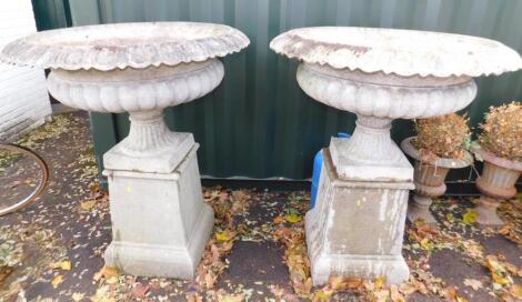 A pair of faux marble urns on stands