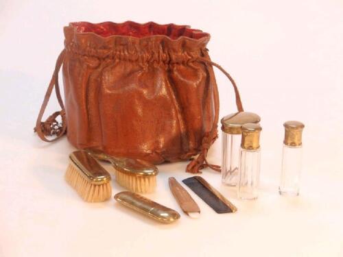 A leather drawstring bag containing a set of miniature toilet accessories