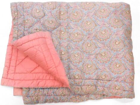 A paisley patterned quilted bed cover.