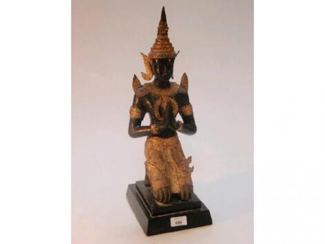 A Nepalese gilt bronze figure of a kneeling deity on an ebonised step plinth