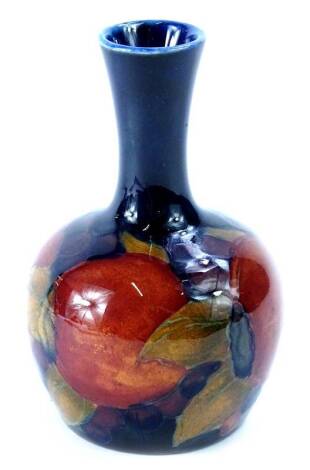 A Moorcroft Pomegranate pattern bottle shaped vase, decorated with fruit, on a cobalt blue ground, indistinct marks to underside, 10cm H.