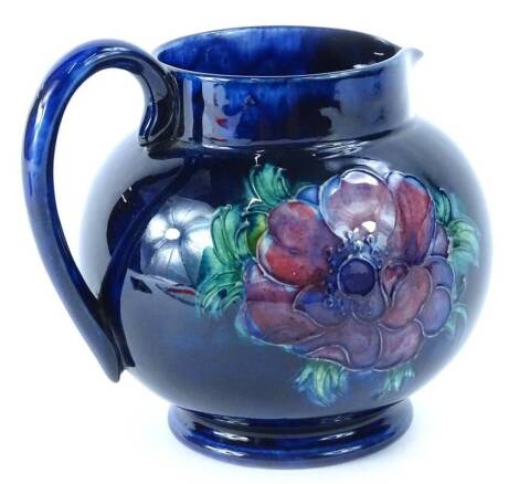 A Walter Moorcroft Anenome pattern pottery jug, on a cobalt blue ground, impressed mark to underside, stamped Made in England, 13cm H.