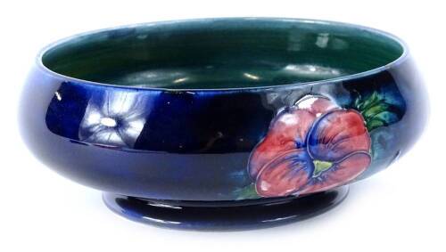 A William Moorcroft Pansy pattern shallow bowl, hand scripted mark and impressed potter to the Queen, 15cm diameter.