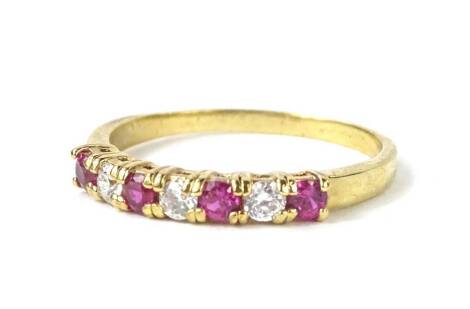 A modern dress ring, set with four pink paste stones, and three white paste stones, each in claw setting, on a gold plated band, of modern design, boxed.