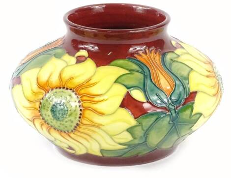 A Moorcroft pottery vase, with tube lined decoration of sunflowers etc., on a Burgundy coloured ground, impressed marks to underside etc., 17cm diameter.