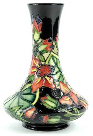 A Moorcroft pottery bottle shaped vase, decorated with purple and pink flowers, with leaves on a black ground, handwritten and impressed marks to underside, 20cm H.