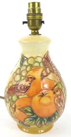 A Moorcroft lamp base, decorated with birds amongst fruit on a peach ground, impressed marks to underside, 20cm H.