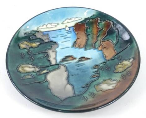 A Moorcroft Rock of Ages design plate, decorated with cliff and seascape, designed by Walter Moorcroft and tube-lined by Gillian Powell, number 13 of a numbered edition, signed and impressed marks to underside, 16m diameter, boxed.