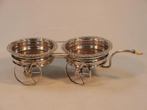 A 19thC silver plated double wine coaster table carriage with reeded handle and ivory knop