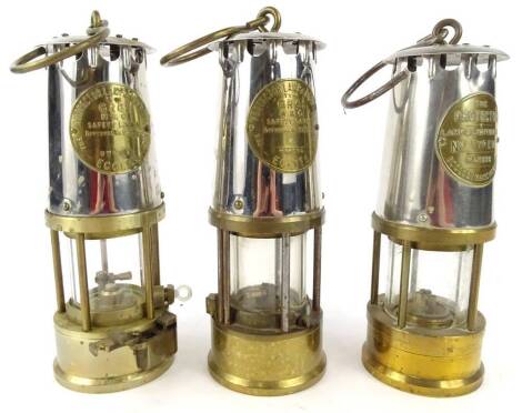 Three chrome plated and brass miner's lamps, all three are The Protector made in Eccles Manchester.