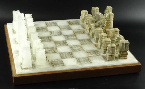 A Continental onyx chess set, the pieces with square form and a board with a mahogany plinth, the board 44cm W.