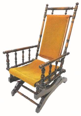 A 19thC American type rocking chair, with spindle turned decoration, a padded back and seat, on shaped end supports with castors.