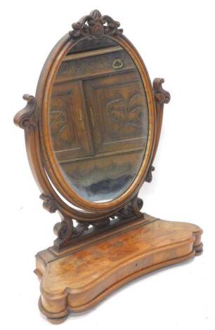 A Victorian figured mahogany dressing table mirror, with oval plate on shaped pierced supports, the base with a moulded edge, hinged to reveal a recess on bun feet, 72cm W.