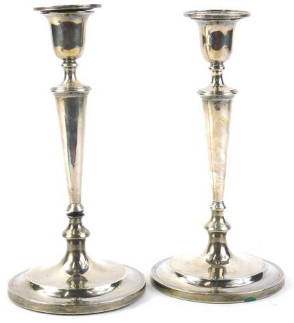 A pair of Edwardian silver candlesticks, each with tapering column, reeded sconce, loaded, 25¾oz gross, 23.5cm H.