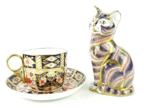 A Royal Crown Derby Imari porcelain cat, with gold button, and a Royal Crown Derby Imari pattern cup and saucer. (3)