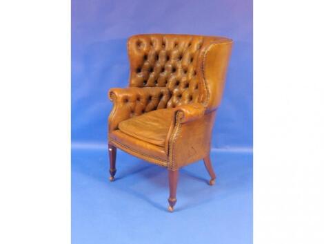 A mid 20thC mahogany framed wing back tub chair upholstered in buttoned