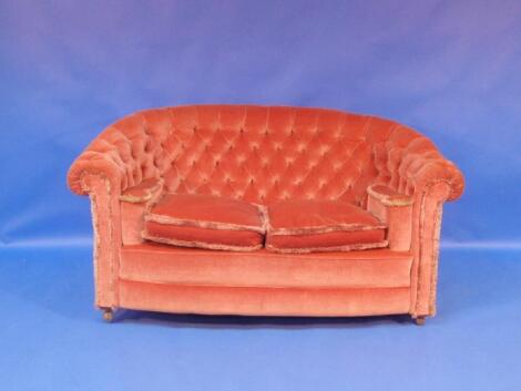 An early 20thC sofa upholstered in pink button draylon